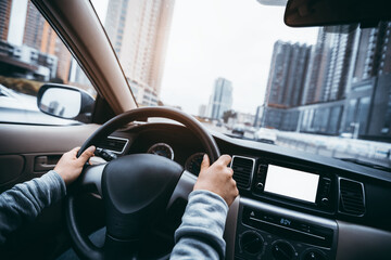 Hands holding steering wheel while driving car on city road