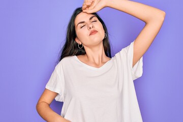 Young beautiful brunette woman wearing casual white t-shirt over purple background stretching back, tired and relaxed, sleepy and yawning for early morning