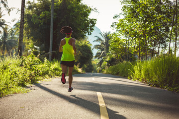 Young fitness woman running o tropical forest trail