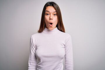 Young beautiful brunette girl wearing casual sweater standing over isolated white background afraid and shocked with surprise expression, fear and excited face.