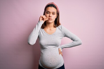 Young beautiful teenager girl pregnant expecting baby over isolated pink background mouth and lips...