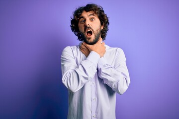 Young handsome business man with beard wearing shirt standing over purple background shouting suffocate because painful strangle. Health problem. Asphyxiate and suicide concept.