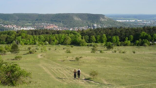 A couple walking down a hill into the city of Jena, Germany, with view to the thuringian forest
