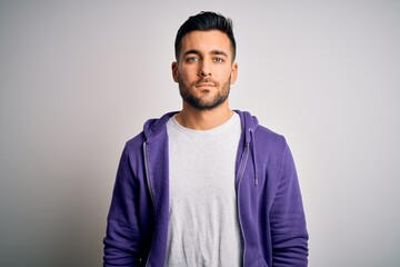 Young handsome man wearing purple sweatshirt standing over isolated white background with serious...