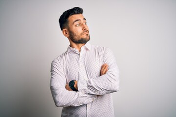 Young handsome man wearing elegant shirt standing over isolated white background looking to the side with arms crossed convinced and confident