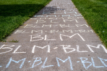 Black Lives Matter BLM written in chalk on a sidewalk in Maple Grove, Minnesota after the death of and resulting protests for change