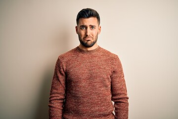 Obraz premium Young handsome man wearing casual sweater standing over isolated white background depressed and worry for distress, crying angry and afraid. Sad expression.