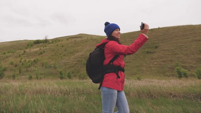 Healthy cheerful woman travels and photography nature by phone. free Young girl tourist blogger records selfie videos at foot of mountains using smartphone with a beautiful landscape in background.