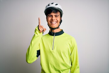 Young handsome cyclist man wearing security bike helmet over isolated white background pointing finger up with successful idea. Exited and happy. Number one.