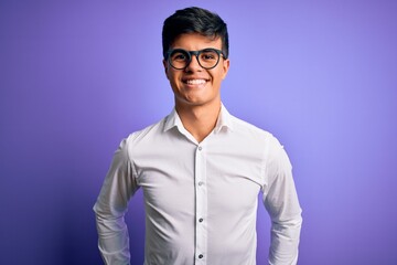 Young handsome business man wearing shirt and glasses over isolated purple background with a happy and cool smile on face. Lucky person.