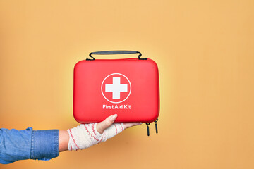 Wounded hand of caucasian young woman cover with bandage holding first aid kit briefcase over...