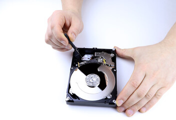 A hand repairs hard drive. Man hand with screwdriver fixing hard drive, disc. A technician repairing a hard disk.