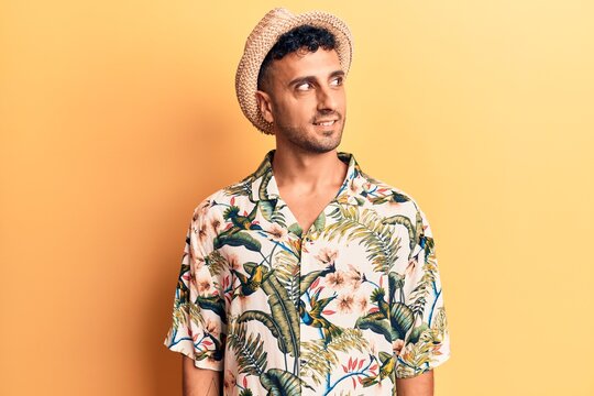 Young hispanic man wearing summer hat looking to side, relax profile pose with natural face and confident smile.