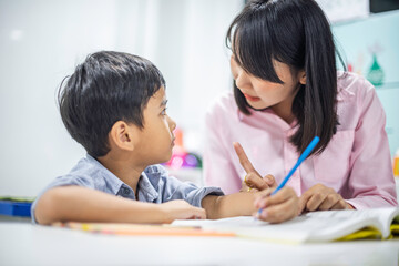 Asian female teacher teaching kid writing lesson and reading book in classroom,Kindergarten pre school concept
