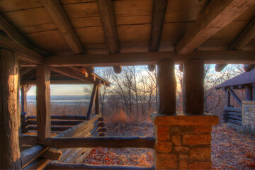 Fototapeta na wymiar looking out from a old rustic wood and stone structure to see the Illinois river in the distance through the trees, setting sun is illuminating land in golden light, HDR photo 