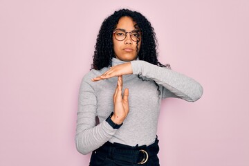 Young african american woman wearing turtleneck sweater and glasses over pink background Doing time out gesture with hands, frustrated and serious face