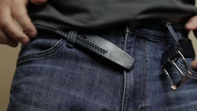 man fastens belt on trousers

