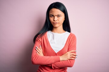Young beautiful chinese woman wearing casual sweater over isolated pink background skeptic and...