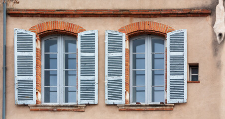 Fototapeta na wymiar Windows with shutters on the wall of the old house