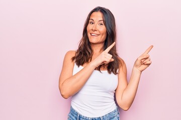 Young beautiful brunette woman wearing casual sleeveless t-shirt over white background smiling and looking at the camera pointing with two hands and fingers to the side.