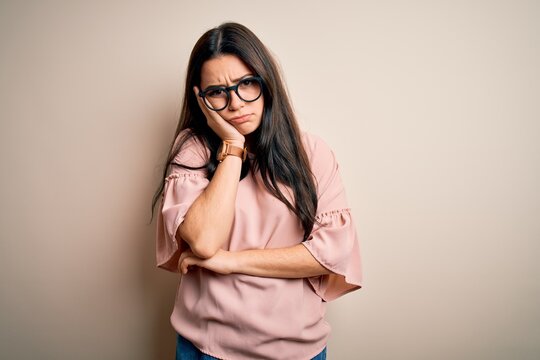 Young brunette elegant woman wearing glasses over isolated background thinking looking tired and bored with depression problems with crossed arms.