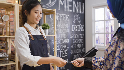 smiling coffee shop girl assistant using pos point of sale terminal to check bill at cafe...