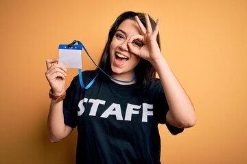 Young brunette worker woman wearing staff t-shirt as uniform showing id card with happy face...