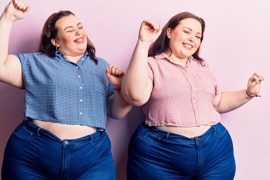 Young plus size twins wearing casual clothes dancing happy and cheerful, smiling moving casual and confident listening to music