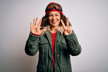 Middle age skier woman wearing snow sportswear and ski goggles over white background showing and pointing up with fingers number seven while smiling confident and happy.