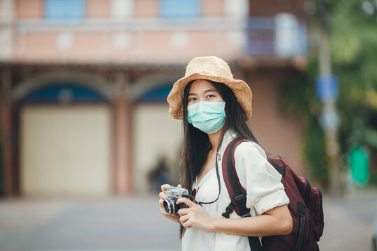 Asian woman backpacker wearing mask travel after pandemic of coronavirus, Young girl wearing hat backpack traveling in street.