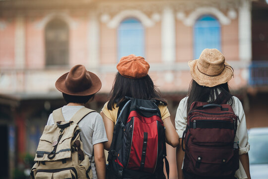 Behind view of woman group backpacker travel on street together, Friendship traveller backpack travel for new experience. Asian girl team traveling Thailand trip.