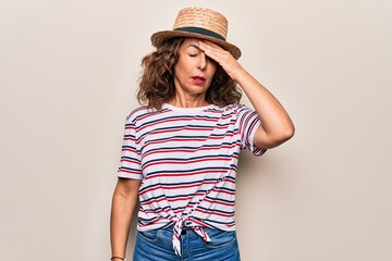 Middle age beautiful woman wearing striped t-shirt and hat over isolated white background surprised with hand on head for mistake, remember error. Forgot, bad memory concept.