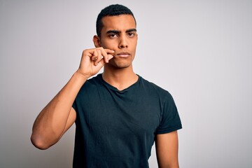 Young handsome african american man wearing casual t-shirt standing over white background mouth and...