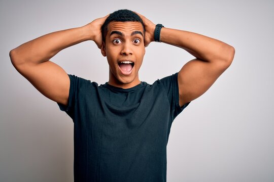 Young handsome african american man wearing casual t-shirt standing over white background Crazy and scared with hands on head, afraid and surprised of shock with open mouth