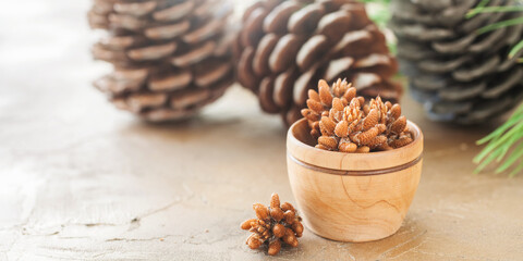 fir-tree kidneys in a wooden bowl and cones on a table, selective focus