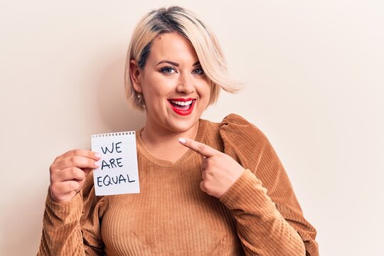 Beautiful blonde plus size woman asking for equality holding paper with we are equal message smiling happy pointing with hand and finger