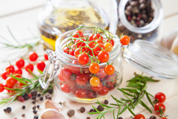 tomatoes in a jar, rosemary and garlic on a wooden background, selective focus