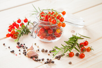 tomatoes in a jar, rosemary and garlic on a wooden background, selective focus