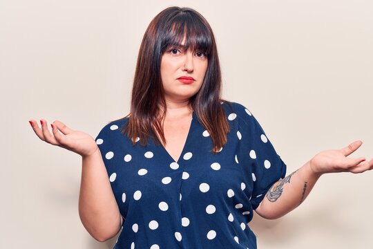 Young plus size woman wearing casual clothes clueless and confused expression with arms and hands raised. doubt concept.