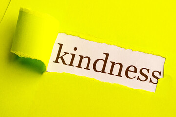 on a light green paper background, a piece of kindness was torn out under it