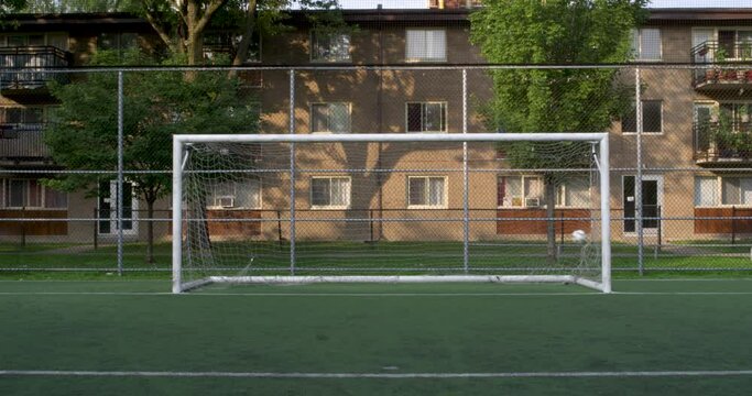 Static shot of a centered soccer goal with a ball hitting the net