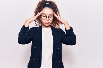 Beautiful kid girl with curly hair wearing business clothes and glasses suffering from headache desperate and stressed because pain and migraine. hands on head.