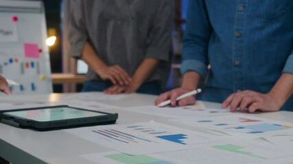 Millennial Asia businessmen and businesswomen meeting brainstorming ideas about new paperwork project colleagues working together planning success strategy enjoy teamwork in small modern night office.