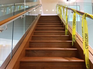 wood and glass staircase with caution tape