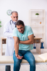 Obraz premium Injured young man visiting old doctor