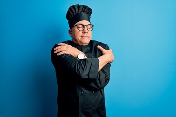 Middle age handsome grey-haired chef man wearing cooker uniform and hat Hugging oneself happy and positive, smiling confident. Self love and self care