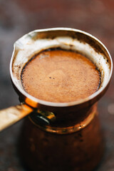 Hot coffee in turkish copper coffee pot (cezve) close up