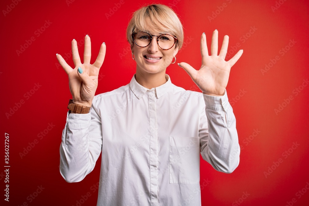 Poster Young blonde business woman with short hair wearing glasses over red background showing and pointing up with fingers number nine while smiling confident and happy.