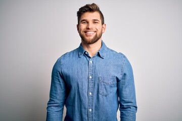 Young handsome blond man with beard and blue eyes wearing casual denim shirt with a happy and cool smile on face. Lucky person.