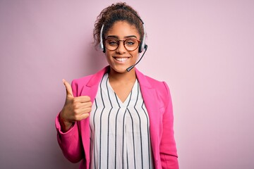 Young african american call center agent girl wearing glasses working using headset doing happy...